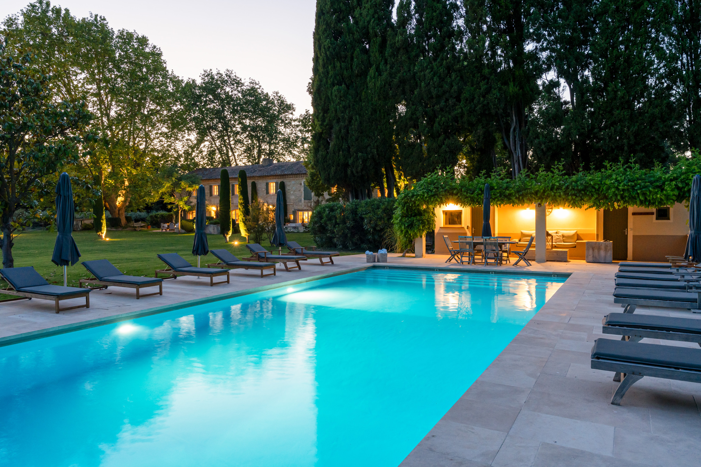 Illuminated pool and stone villa at dusk